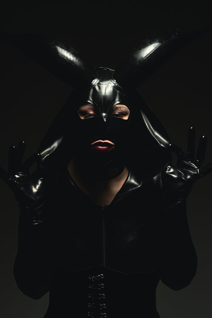Dark and moody studio portrait of a woman in a leather costume with horns.